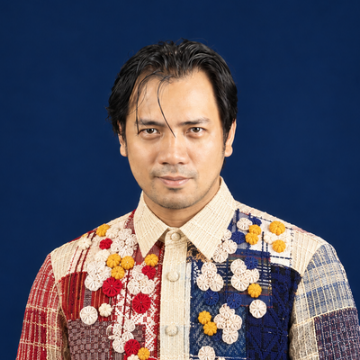 Man wearing a patchwork-style Barong Tagalog on dark blue background